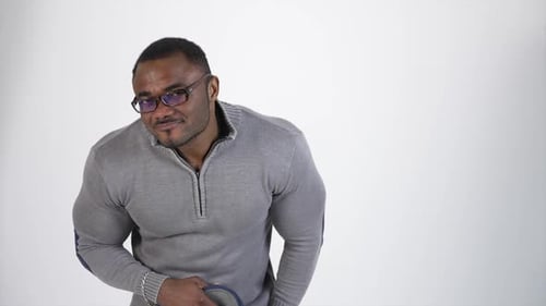 Rätselhafter afrikanischer Mann isoliert auf weiß. Hübscher Afroamerikaner mit Brille und grauem Pullover