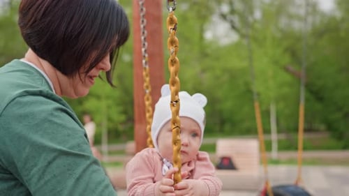 Woman and Infant on Tire Swing in Park