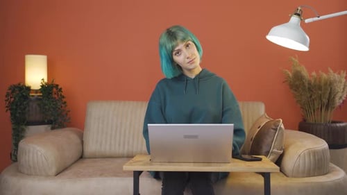 Young Woman with Teal Hair Speaking on Laptop