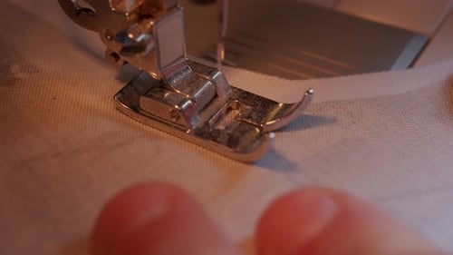 Ansicht von oben auf Nadel und Fuß der Nähmaschine, die sich langsam durch den Stoff bewegen.