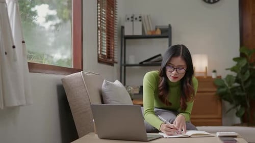 Woman wears green sweater working studying and liniving at home.