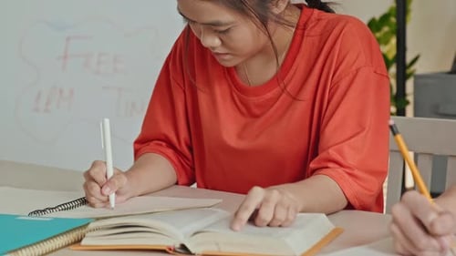 Asian Girl Doing School Assignment in Classroom