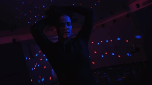 Jolie femme talentueuse dansant une chorégraphie moderne sur fond de néon bleu en studio