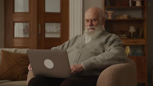 Senior Man Using Laptop Indoors at Home