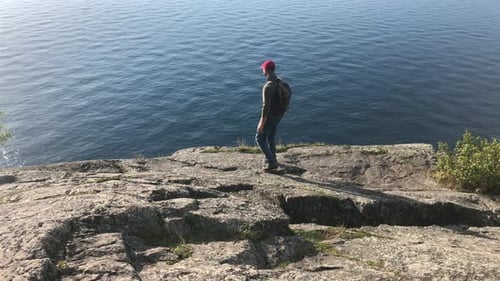 Man, ocean and hiking on rocks with travel, view with nature and environment