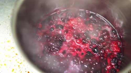 Close-up shot of berries boiling in a metal pot making compote