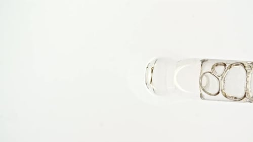 Transparent Cosmetic Gel Fluid Serum with Molecule Bubbles Oil in Pipette Drips on a White