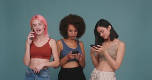 Three Young Women Using Mobile Phones Smiling
