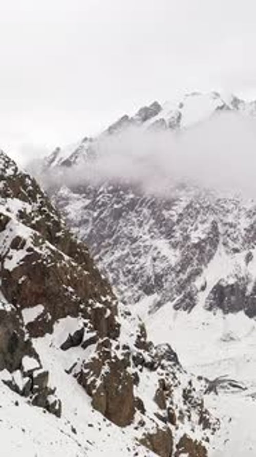 Clouds Enveloping Snowy Mountain Peaks in a Winter Landscape