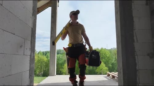 Construction Worker Holding Level in Unfinished Building