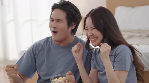 Happy Couple Cheering with Popcorn at Home