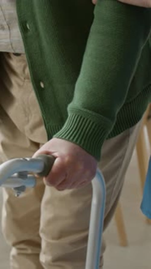 Senior Man Walking with Walker Supported by Female Caregiver Vertical