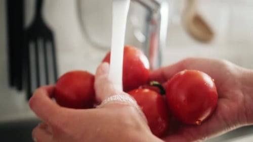 Primer plano de las manos: lavar tomates rojos frescos en el fregadero de la cocina Concepto de alimentación saludable Cosecha verano