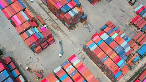 Luftaufnahme von einer Drohne, die über viele Frachtcontainer fliegt