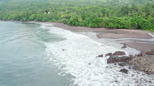 Slow Motion Aerial View of White Waves Crashing on Dark Pebble Beach in Flores