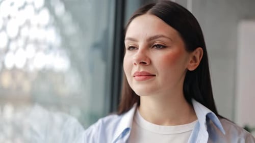 Woman in Shirt Looks Out Window Dreamily