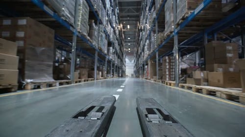 Forklift trucks moving cardboard boxes through a modern logistics warehouse