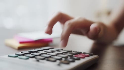 Hand press calculator to calculate income expenses and plans for spending money on home office.