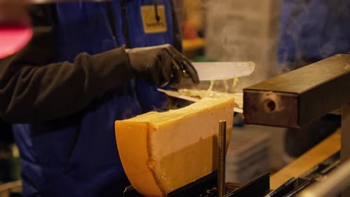 Roulette à fromage fondante 4K utilisée pour fabriquer une raclette au fromage traditionnelle sur un stand de marché de Noël, à Vienne