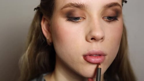 crayon de maquillage sur les lèvres d'un mannequin blond gros plan à main