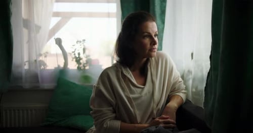 Woman Sitting Thoughtfully Looking Out a Window