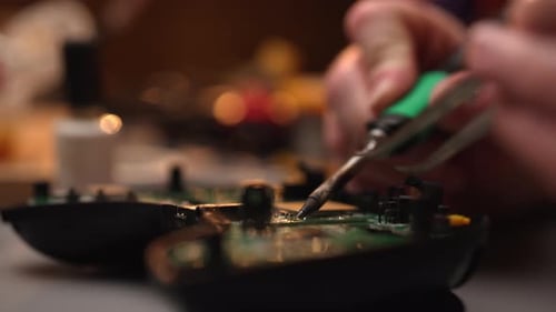Technician Soldering Circuit Board with Tweezers Close Up