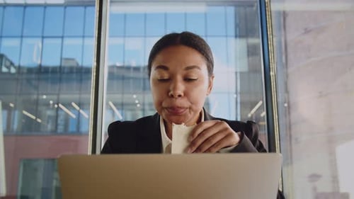 Junge afroamerikanische Frau isst bei der Arbeit Schwarze Frau im Büro isst Sandwich zum Frühstück