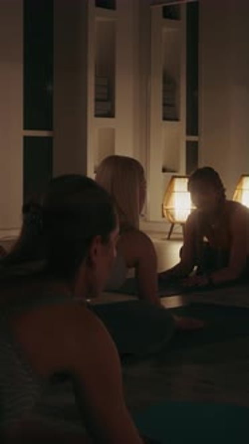 Women Stretching During Yoga in Dimly Lit Studio