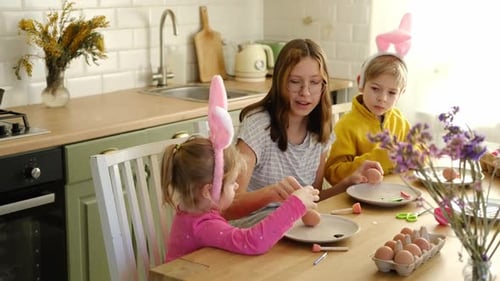 Kinder, Geschwister, die Osterei bemalen, zusammen am Tisch sitzen, Ostern, Familientraditionen, Jugendliches Mädchen