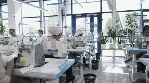 Moderne Textilfabrik mit Arbeitern, die Nähmaschinen in einer effizienten industriellen Umgebung einsetzen