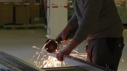 Arbeiter schneidet Industriestahlträger mit einem Trennscheiben-Winkelschleifer
