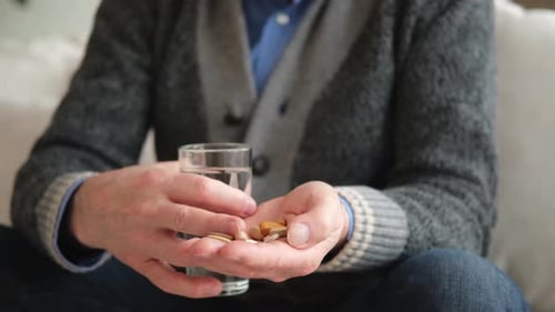 Senior Holding Pills and Glass of Water
