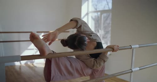 Girl Stretches and Puts Her Foot on a Ballet Bar During Her Classical Dance Training and Rehearsal