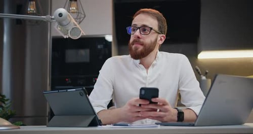 Man Using Smartphone with Laptop and Tablet at Home