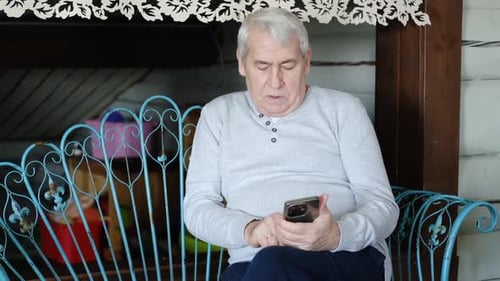 Mature Man Using Smartphone While Relaxing Indoors