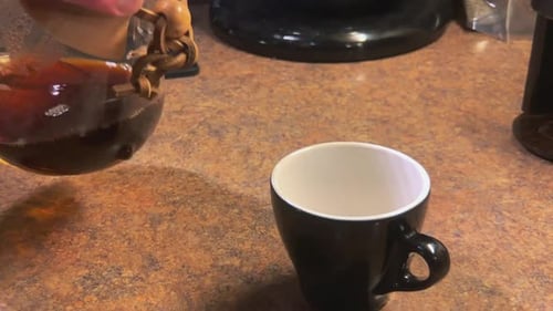 Pouring Freshly Brewed Coffee into Black Mug