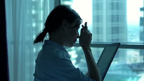Young businesswoman browsing internet on tablet by window at luxury home
