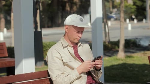 Man Sitting On Bench Using Smartphone