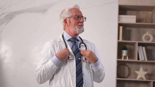 Médico senior maduro con gafas y uniforme médico en el hospital o en el consultorio del médico general