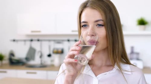 Junges süßes Mädchen trinkt Netzwasser aus Glasbecher. Ein Schluck Reinheit