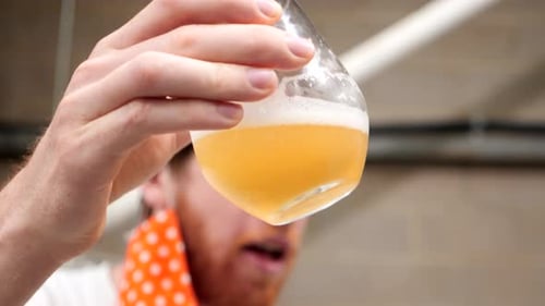 Mann inspiziert ein Bier aus nächster Nähe