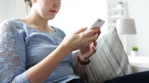 Woman using her smartphone while relaxing at home