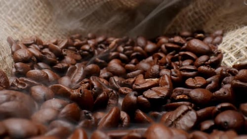 Gros plan de grains de café fraîchement torréfiés dans le sac en toile de jute