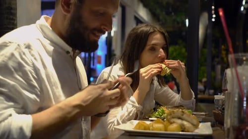 Young Couple Talking and Eating Dinner in Cafe at Night Attractive