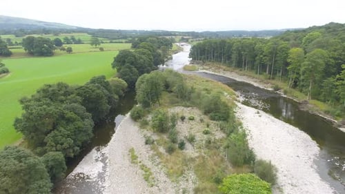 Beautiful drone footage flying over a tree lined shallow, slow moving river and river island in the