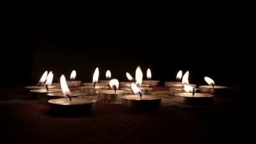 Many Tea Light Candles Flicker in the Dark