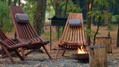 wooden chairs stand by a blazing fire in country hotel in the woods for evening gatherings