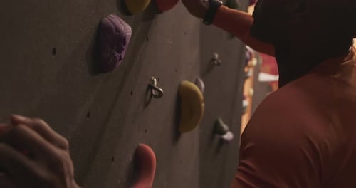 Close-up, High-angle shot of Male Athlete Rock Climber Exercising on Indoor Climbing wall
