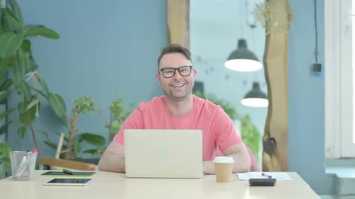 Smiling Man with Laptop at Desk