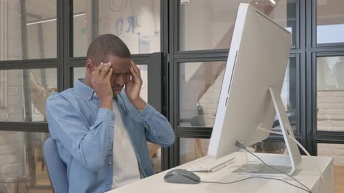 Frustrated Man Rubbing Face at Modern Computer